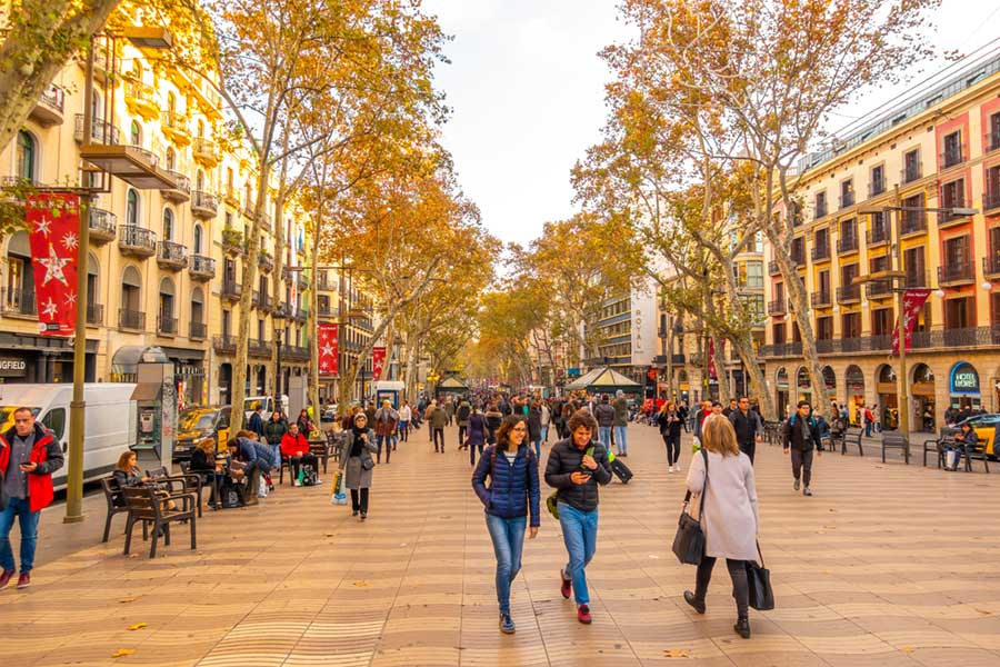 Crowds of people walking along the tree-lined wide pedestrian street of La Rambla