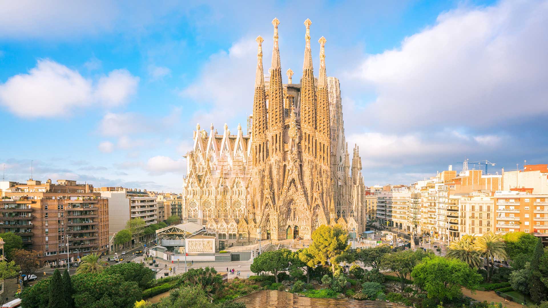 The Sagrada Familia, a yellow church rising above the city with a blue sky in the background