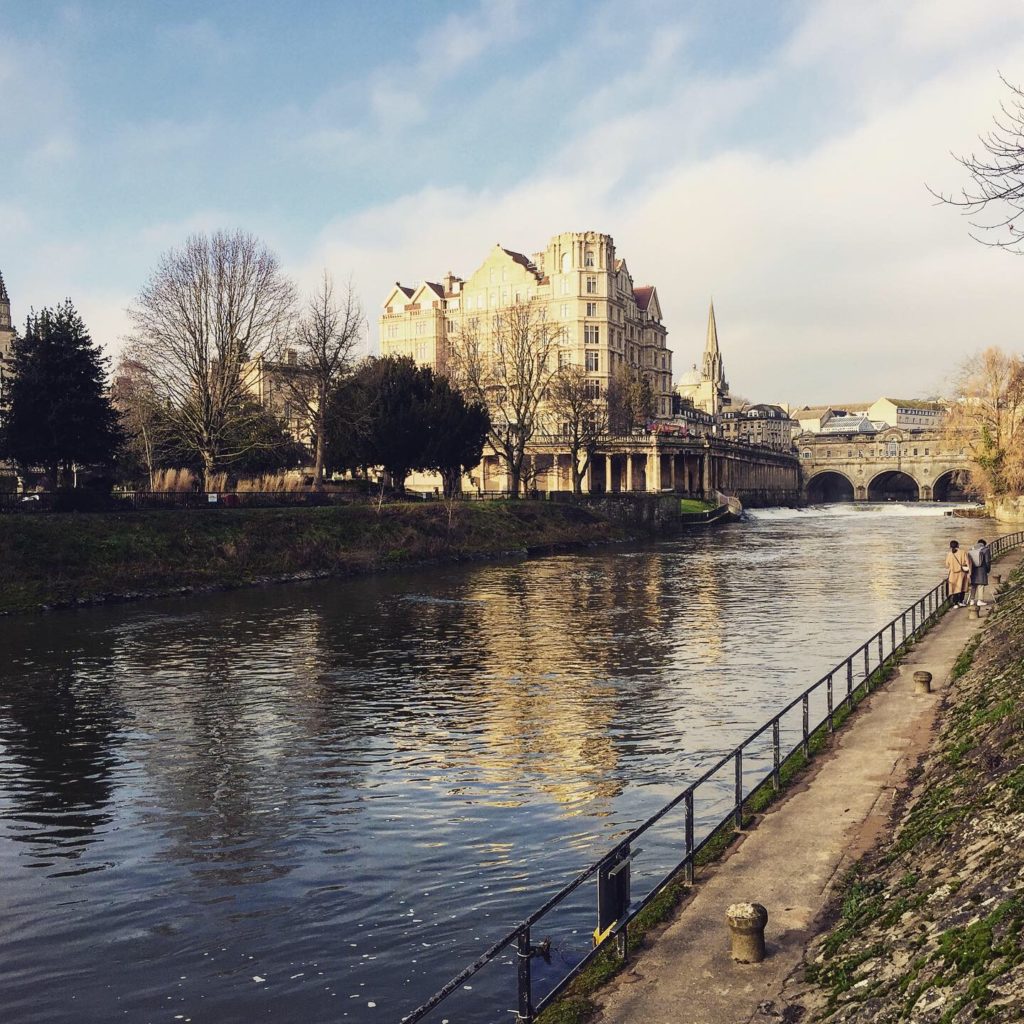 Ornate bridge crossing a river in Bath, church spire in the distance