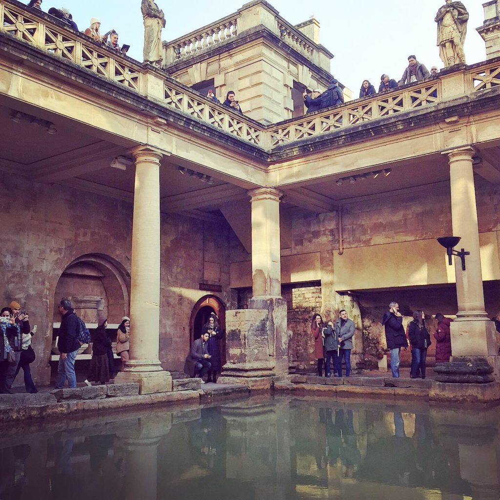 Roman baths, columns, tourists and a green central pond