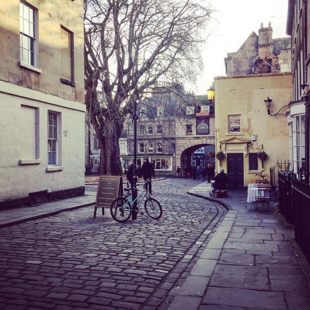 Cobbled street winding through a Georgian arch in Bath