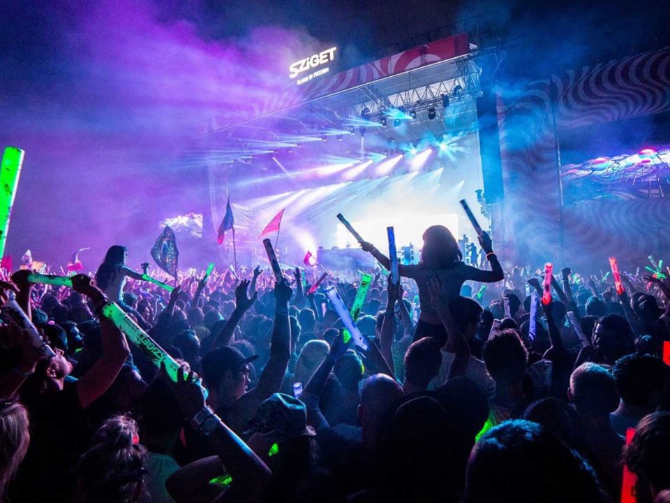 A crowd dancing to music at Sziget main stage with bright fluorescent lights